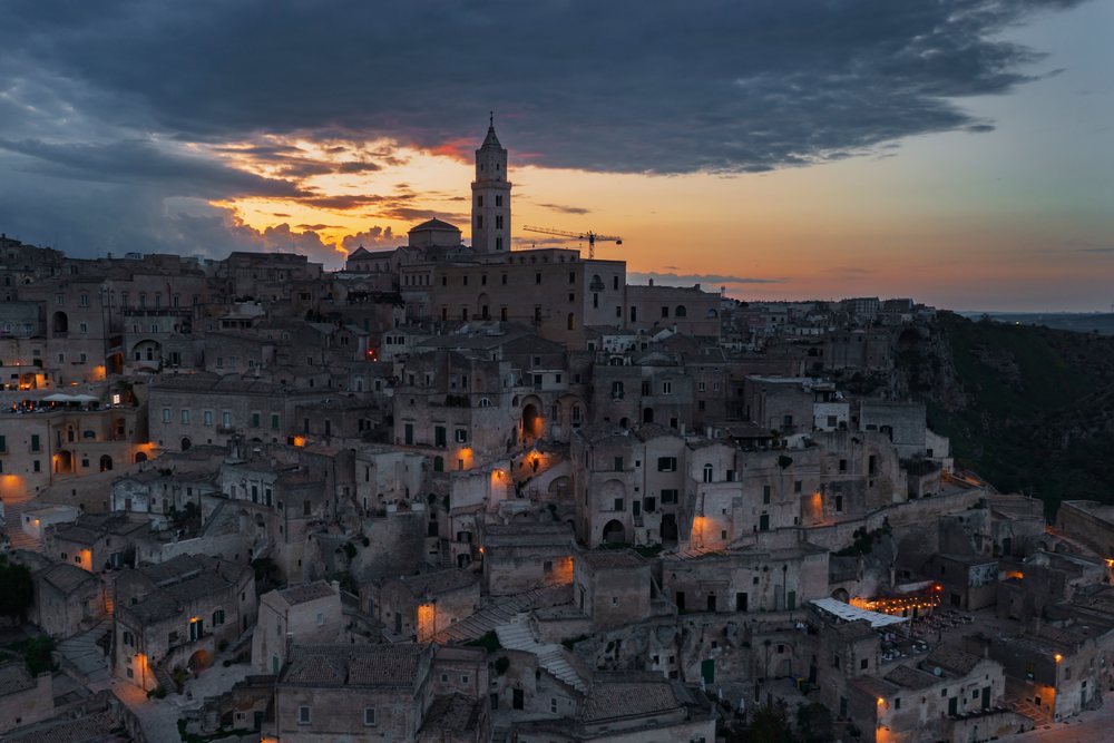 Sasso Caveoso, showing ancient stone houses and a tower at Sunset under a cloudy sky, Matera, Basilicata, Italy.