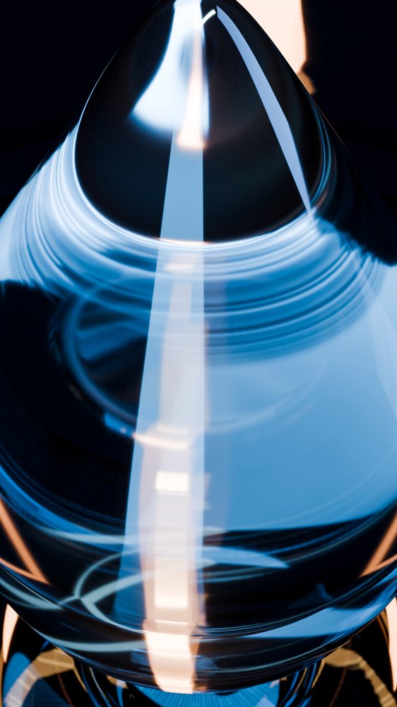 Close-up of a transparent glass cone reflecting blue light in a studio setting.