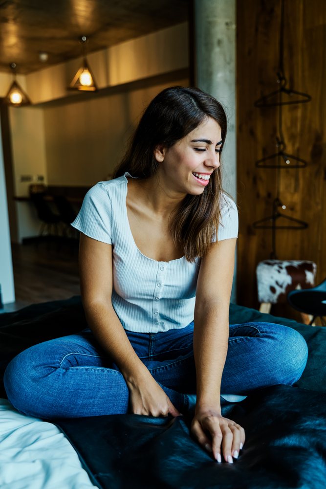 A young woman relaxes smiling in a cozy modern room in a hotel