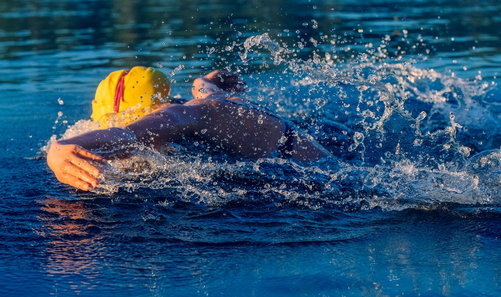 Swimmer performing freestyle stroke with water splashing around in an outdoor pool, USA.