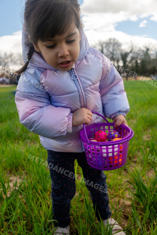 A young white girl holding a purple basket with colorful balls