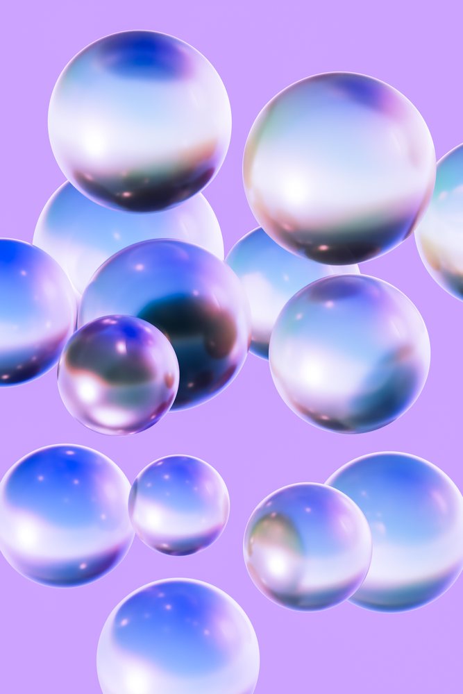 Shiny pearlescent spheres of varying sizes float against a purple background displaying colorful reflections in an abstract composition.