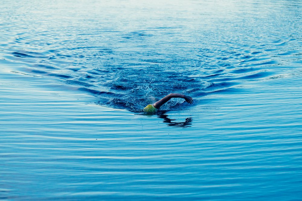 Swimmer wearing a swim cap performing a freestyle stroke in open water, USA.