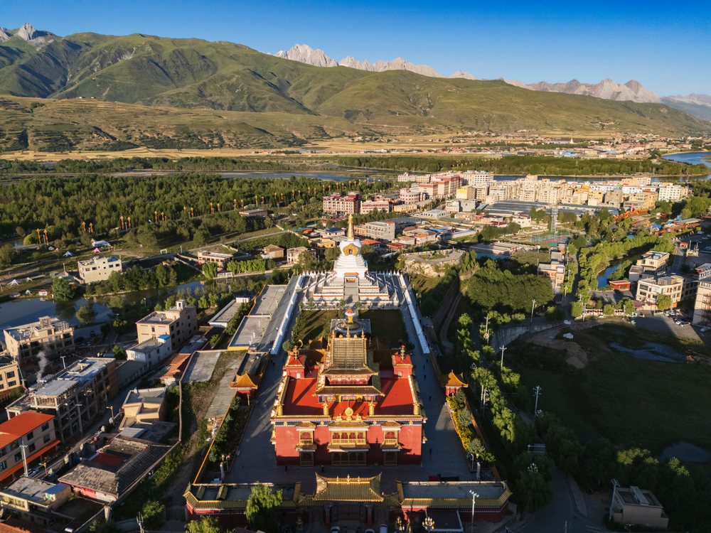 Memorial buildings including Zhu De Commander in Chief and WushiGeda Living Buddha stand at sunrise with mountains and urban area, Garze, Sichuan Province, People's Republic of China.