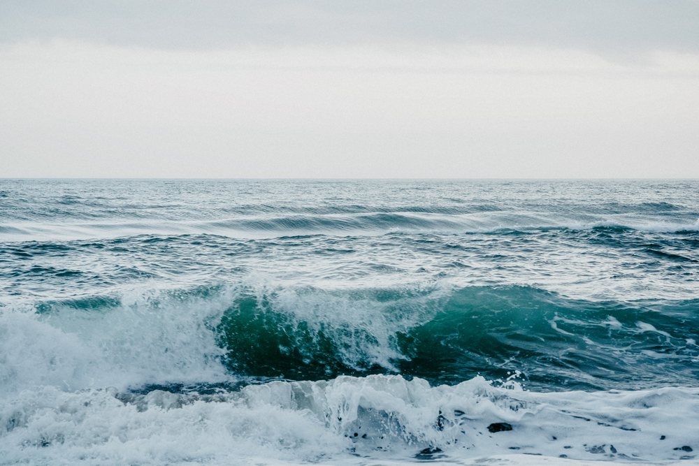 Ocean waves with crest and surf foam rolling under a cloudy sky at sea, Spain.