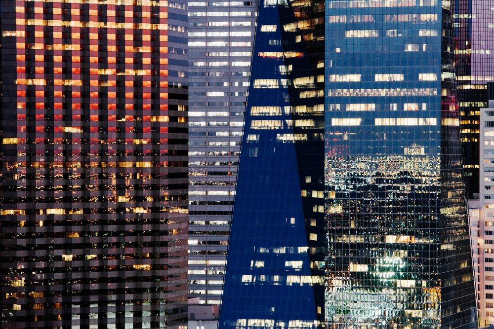 Lit office buildings with glass reflections create a vibrant cityscape at night in downtown, Dallas, Texas.