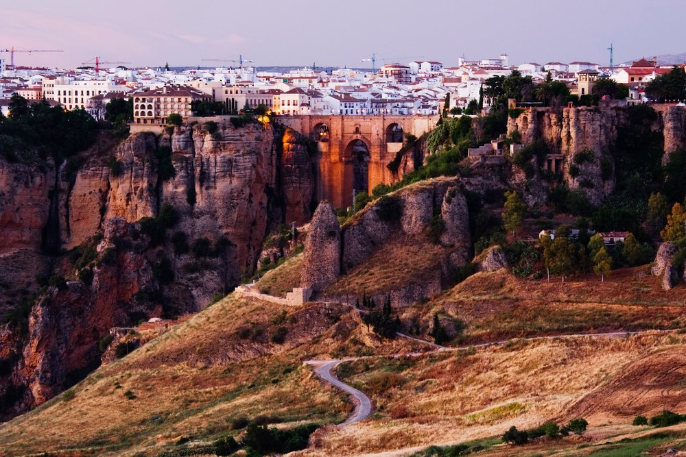 Ronda cityscape featuring the historic Puente Nuevo stone bridge spanning a deep gorge at sunset, Andalucia, Spain.
