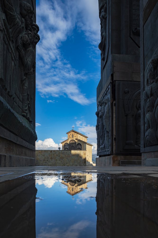 The Chapel of the Annunciation is reflected in a pool among sculpted pillars at the History of Georgia Monument, Cityscapes, Tbilisi.