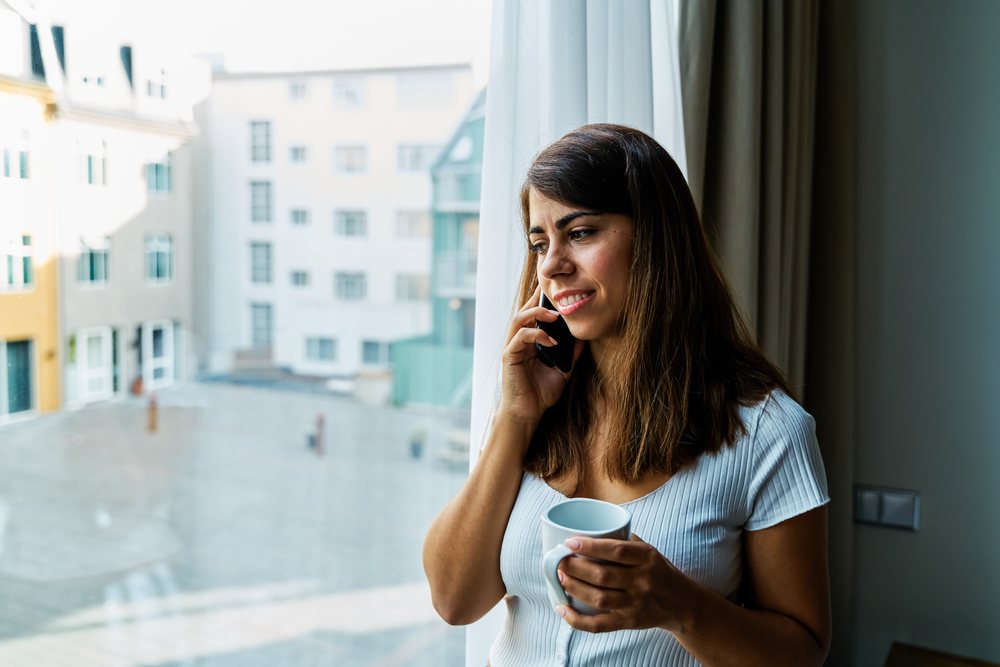 A woman talks on her phone with a mug