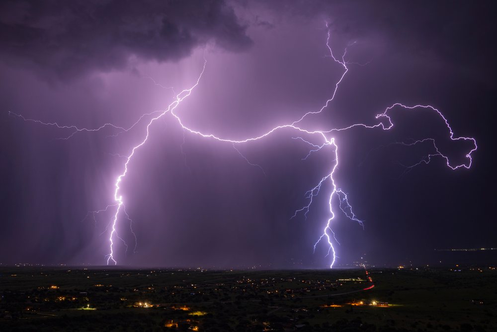 Lightning bolts strike over a distant town under a stormy night sky near Our Lady of the Sierras, Storm Chasing, Weather, Environmental Issues, Sierra Vista, Arizona, USA.