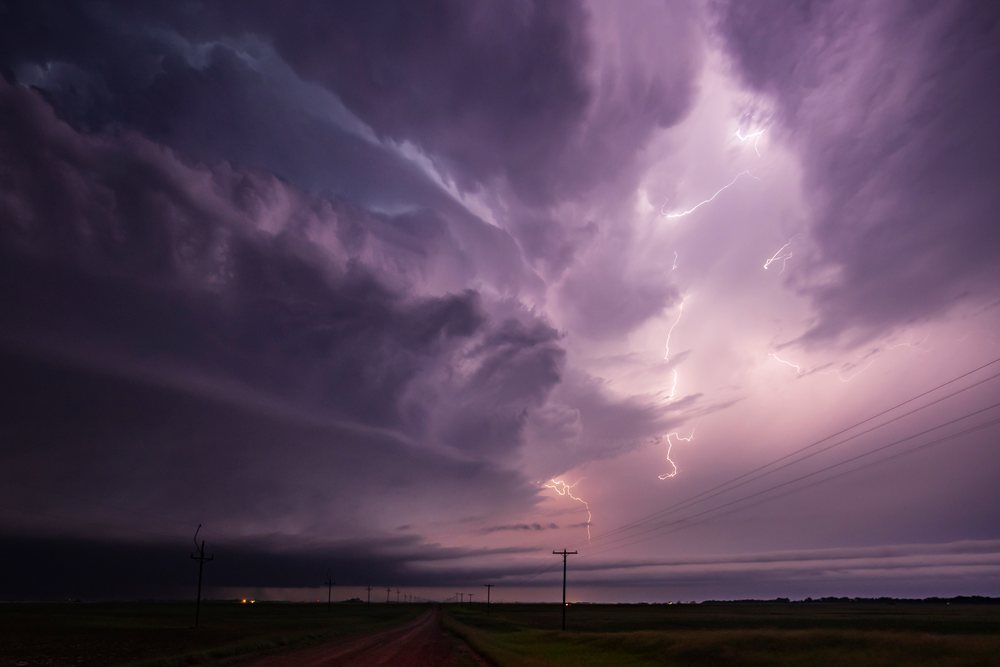 Lightning strikes from a Tornado-Producing Supercell over a rural road with power lines, Storm Chasing, USA, Tornado Alley, Great Plains.