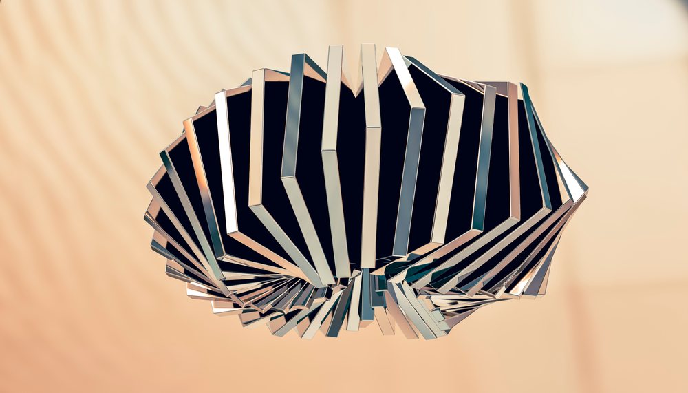 A close-up view of a shiny metal abstract sculpture with geometric design against a soft beige background in a studio setting.