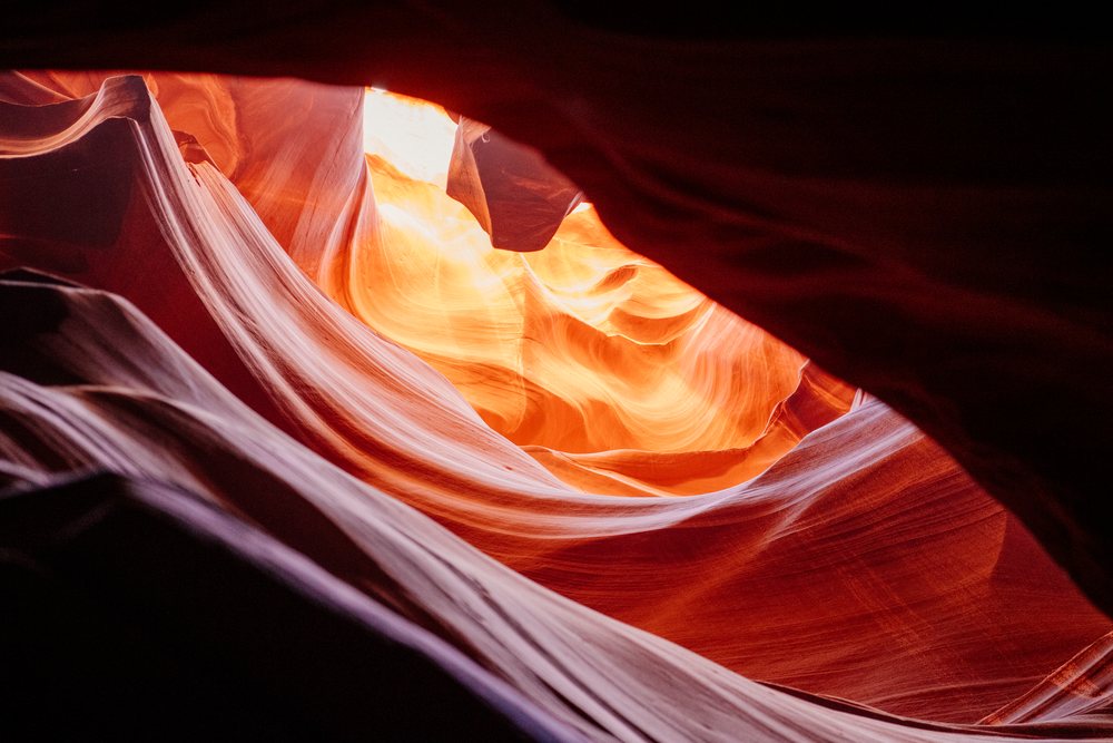 Natural light shines through the opening, illuminating rock formations inside Antelope Canyon, Navajo Land, Arizona, USA.