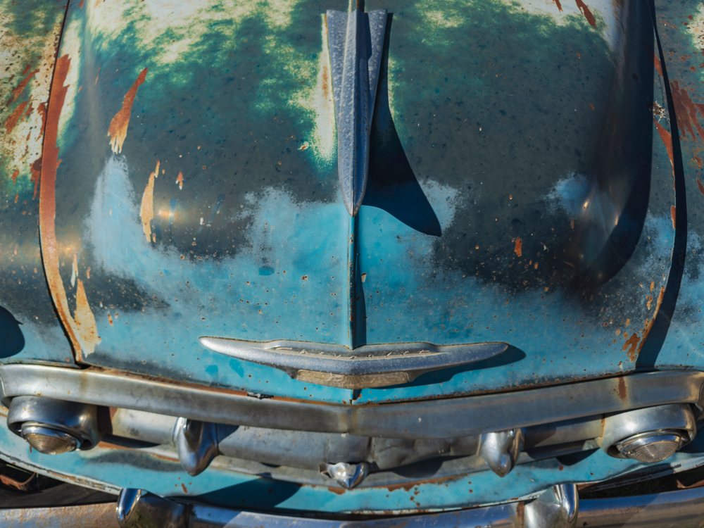Rusty blue vintage car hood and front grill showing weathered metal and paint damage, Americana, Historic, McLean, Texas, USA.