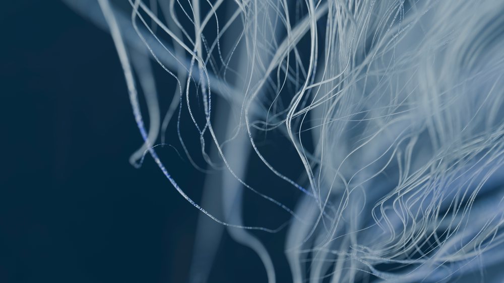 White and delicate fibers are intertwined creating an abstract soft texture against a dark blue background.