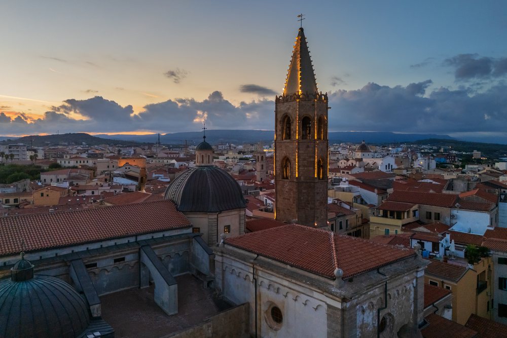 Historic Parrochia Cattedrale dell'Immacolata Concezione church bell tower illuminated at Dawn with Alghero townscape, Travel Images, Sardinia, Italy.