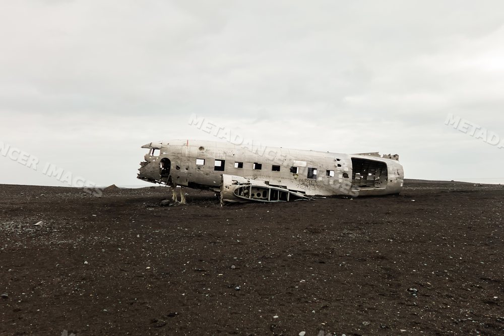 An abandoned crashed airplane fuselage on a black sand desert