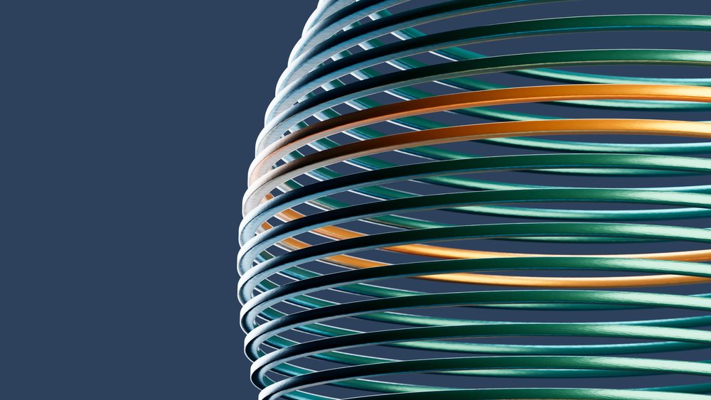 Contemporary colorful spiral sculpture of interlocking green, orange, and white metal rings against a blue studio background.