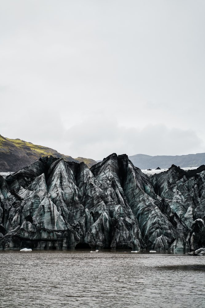A melting glacier with ice peaks and volcanic ash in a glacial lake