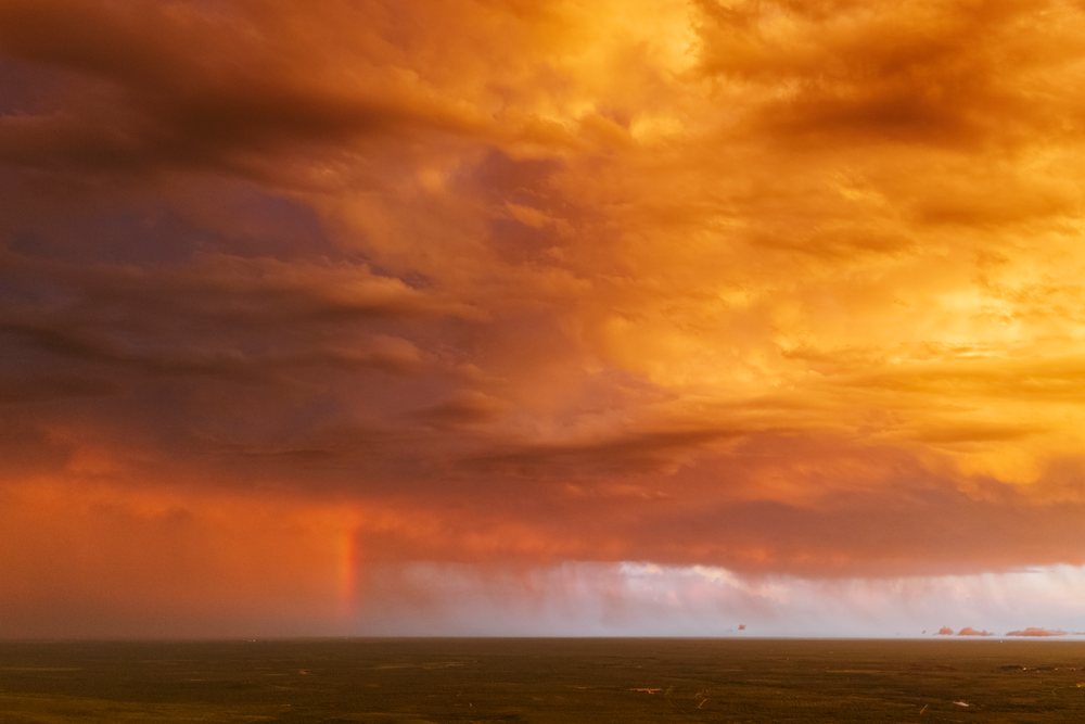Storm clouds with Sunset light and a rainbow over the flat landscape of Uvalde in Tornado Alley, Storm Chasing, Weather, Environment, Texas, USA.
