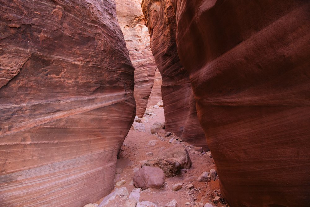 Slot canyon with narrow red sandstone walls and a rocky sandy path, Buckskin Gulch, Utah, USA.