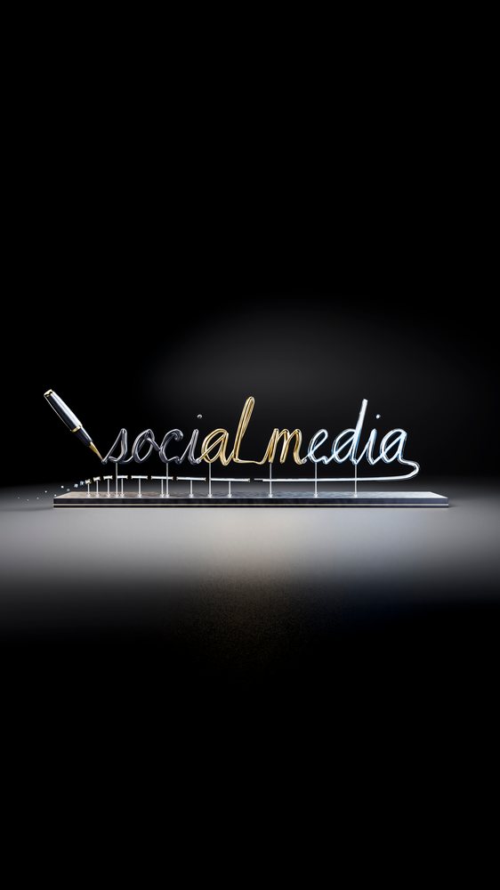 Metal sculpture of the phrase social media in script with a pen on a black reflective surface.