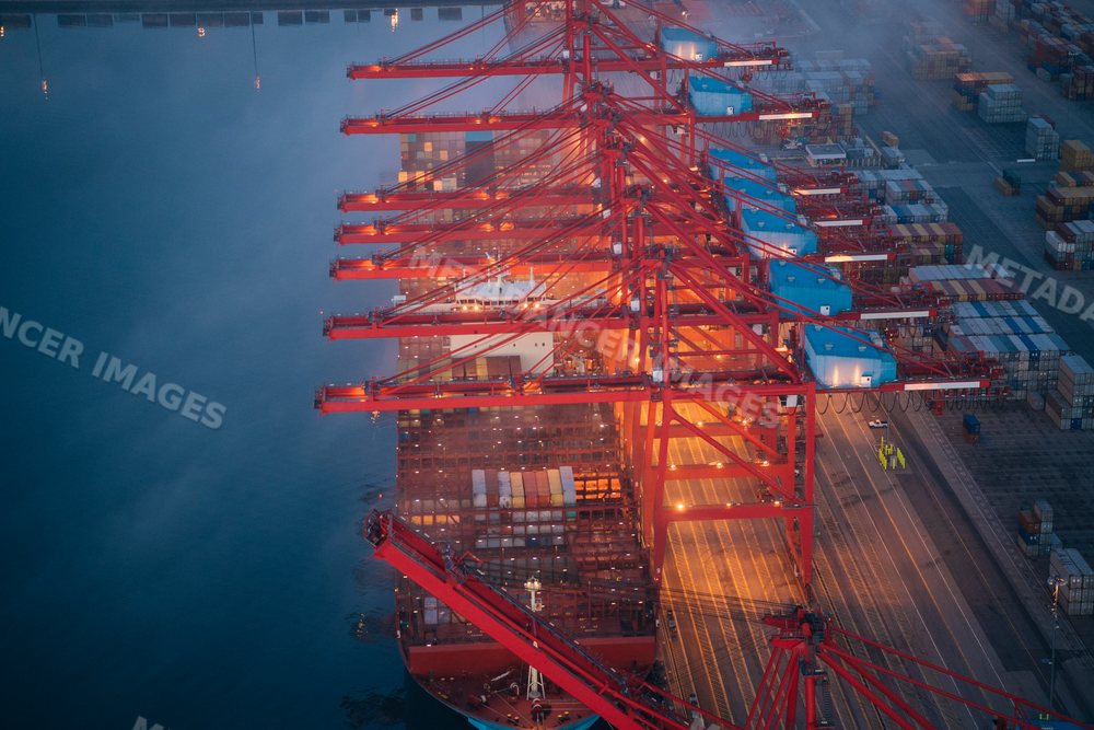 A container ship is loaded with cargo at a busy port in a beach