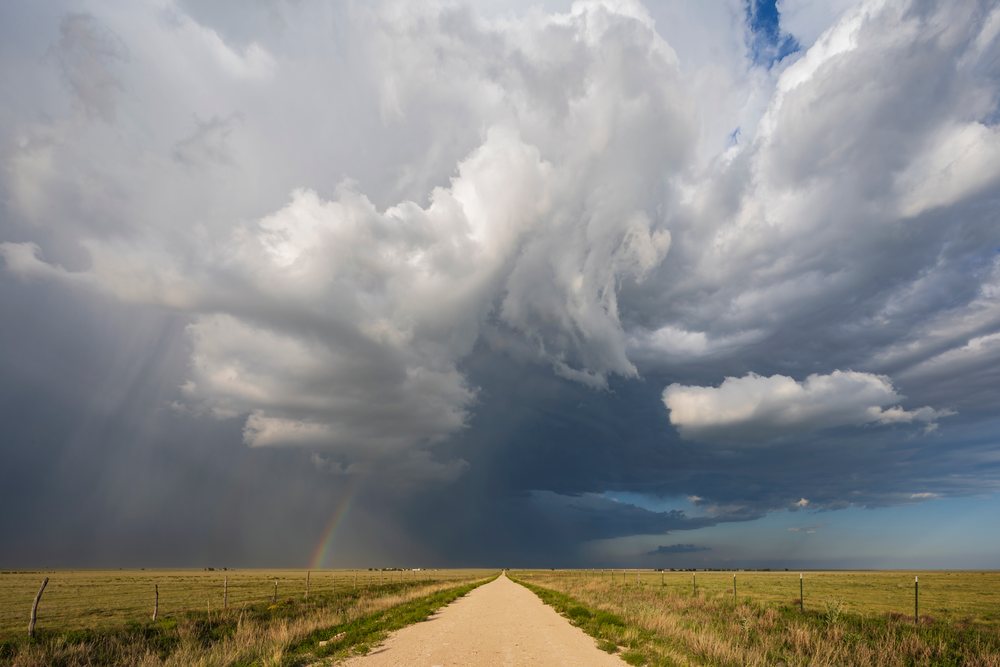 Supercell storm with a Rainbow seen over an open grassland and dirt road, Amistad, New Mexico, USA.
