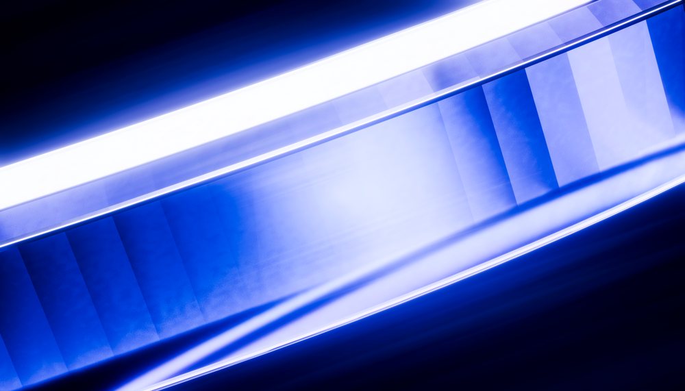 Escalator with blue and white lighting showing modern indoor staircase design.