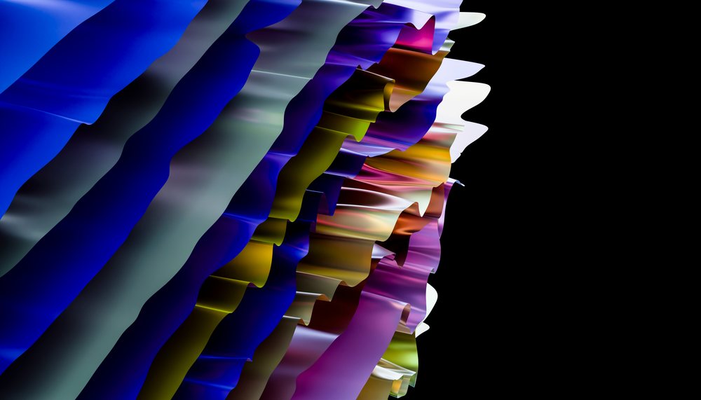 Folded colorful paper sheets arranged abstractly with curved edges and multicolored stripes in a studio environment.