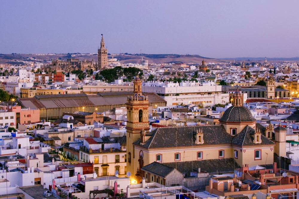 Seville cityscape featuring historic church towers and urban rooftops at evening, Andalucia, Spain.