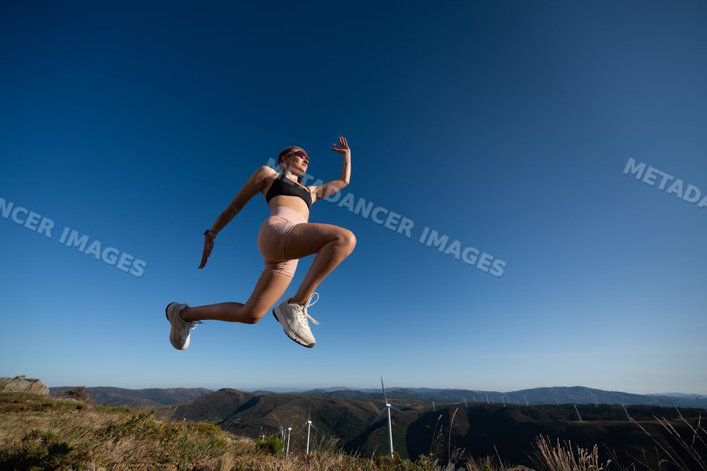 A white woman jumps energetically during an outdoor workout in Galicia