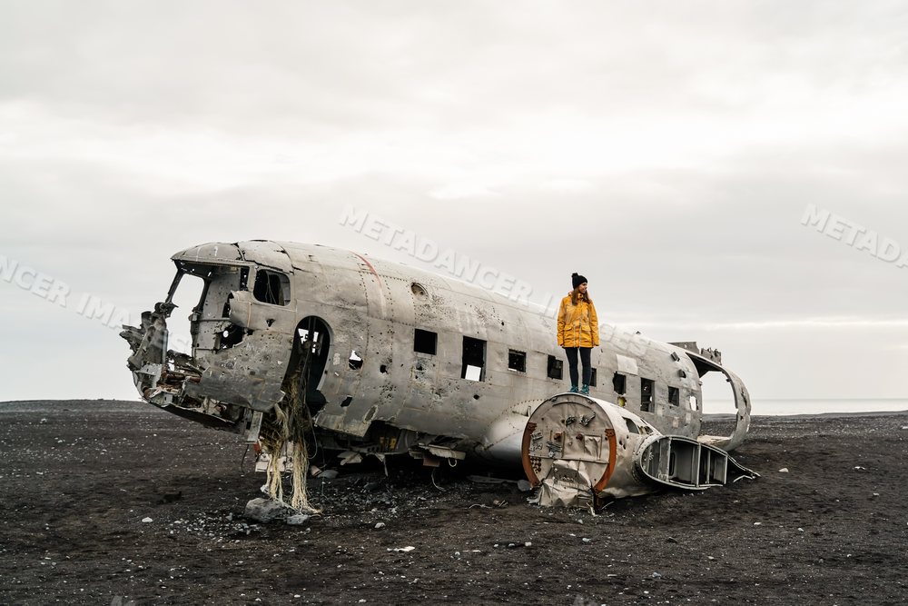 A white woman explores the wrecked airplane fuselage