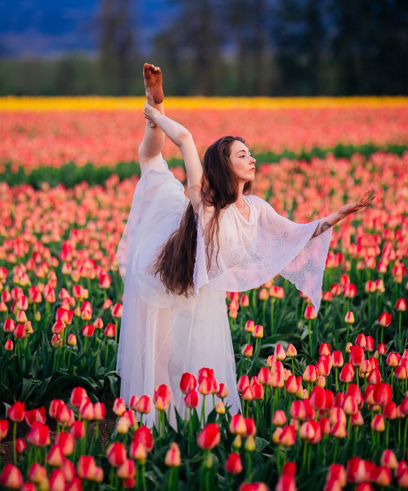 Woman ballet dancer stretches gracefully in a vibrant tulip field during springtime, USA.