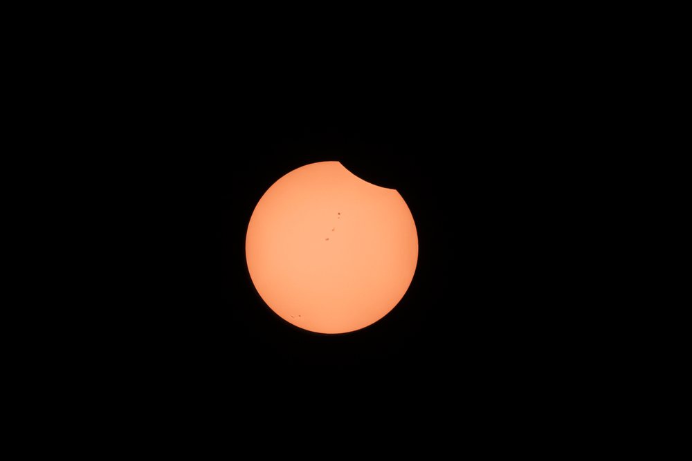 Partial solar eclipse with the moon partially covering the sun and visible sunspots, observed, Los Angeles, USA.