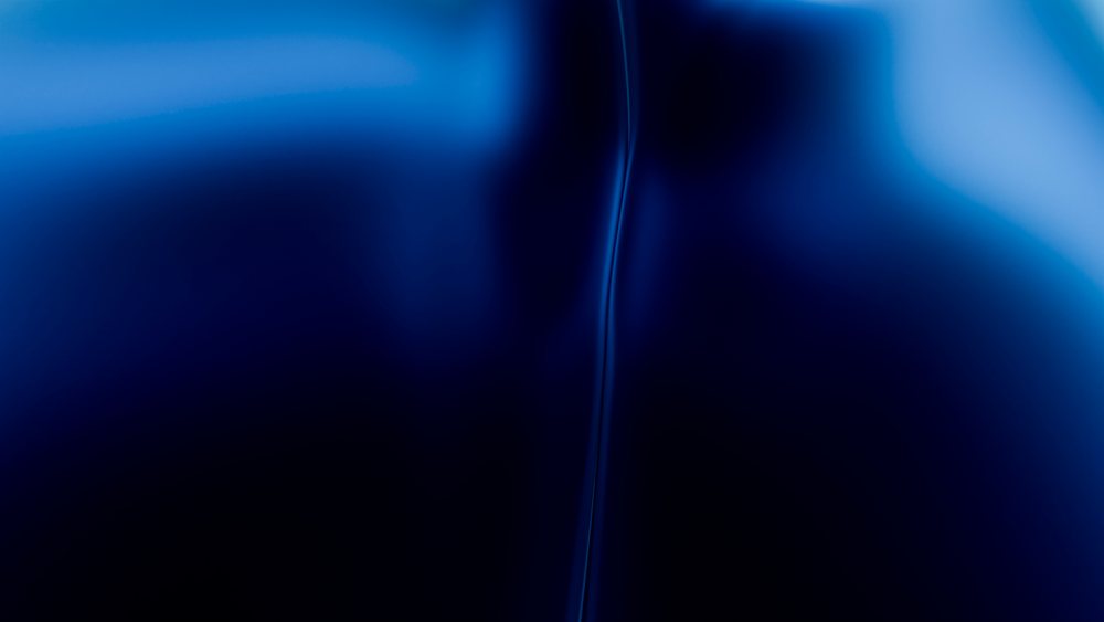 Blue abstract smooth gradient texture featuring a subtle curved line and glossy surface.