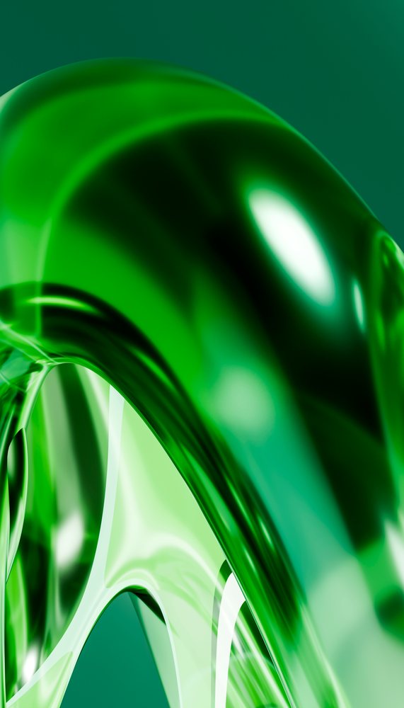 Abstract green glass sculpture with smooth curved surfaces and reflective qualities in a studio setting.