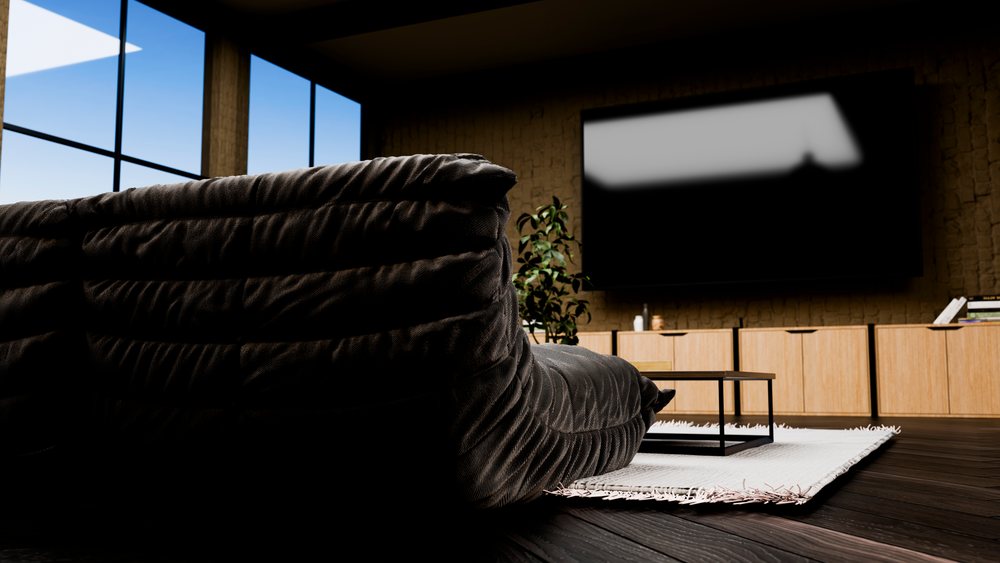Black couch facing a wall-mounted flat screen TV above wooden cabinets in a modern living room.