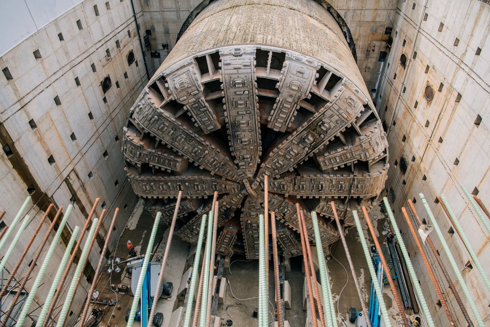 A tunnel boring machine with exposed steel reinforcement bars is set up in a construction site for underground drilling, USA.