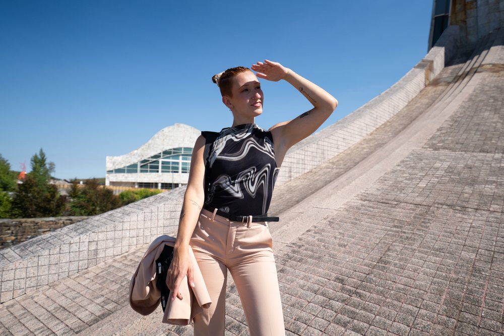 Businesswoman posing outdoors holding a jacket with modern urban architecture and clear blue sky, businesswomen, Spain.