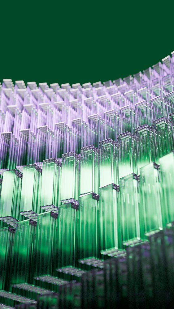 Stacked rectangular glass blocks in green and purple hues form a modern abstract pattern with smooth reflective surfaces.