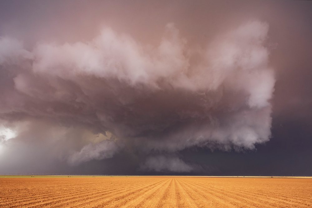 Supercell thunderstorm with massive cloud formation over a brown plowed field in Tornado Alley Great Plains, Storm Chasing, Morton, Texas, USA.
