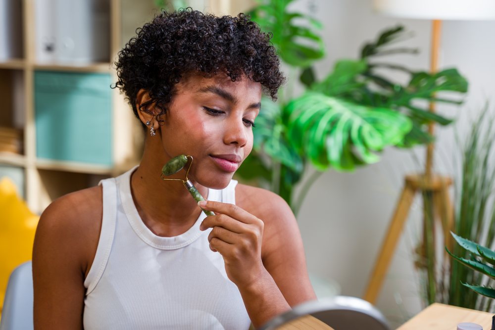 Woman using a jade roller for facial massage at home, Spain.