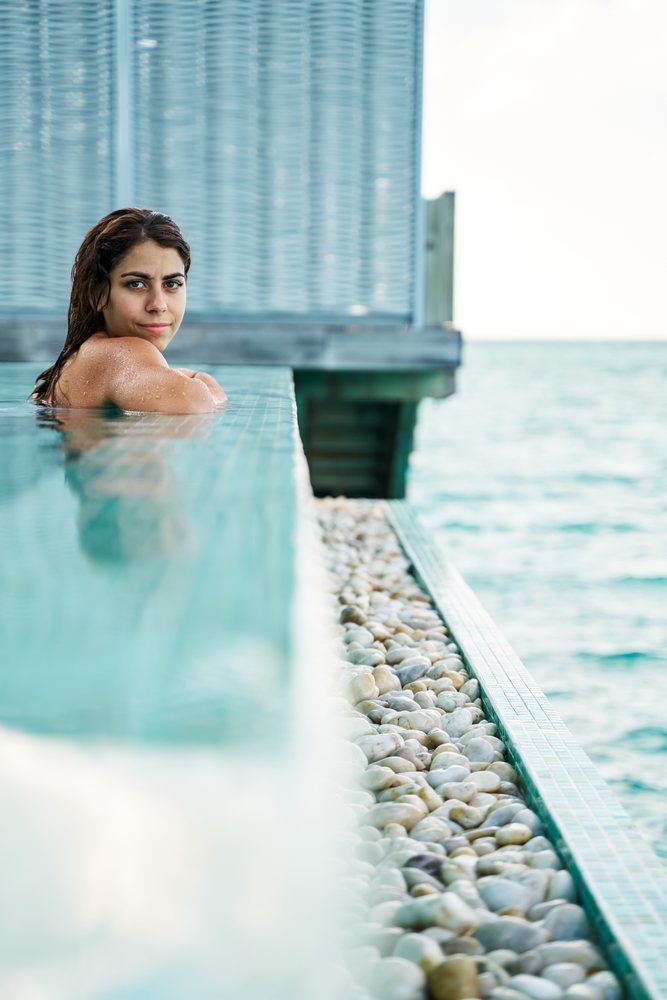 A white woman relaxing in a swimming pool with ocean views