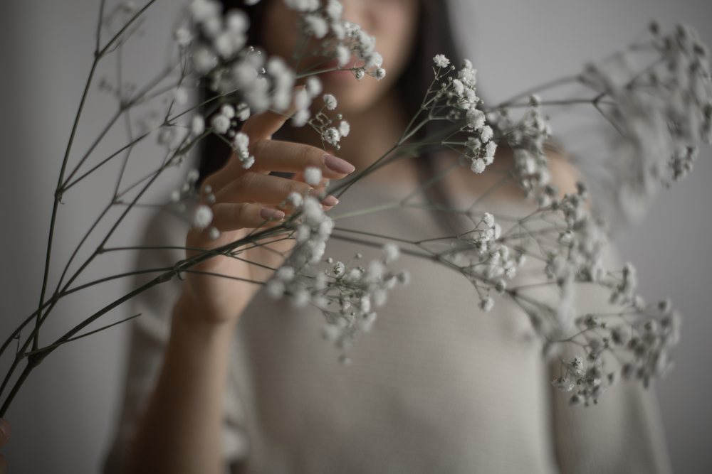 Woman gently holds delicate baby's breath flowers in a minimalist soft focus portrait, Art, emotional.