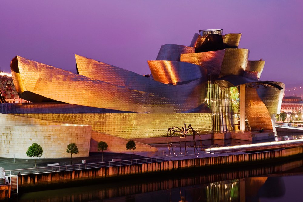 Guggenheim Museum illuminated at night with its lights reflecting on the river, Bilbao, Spain.