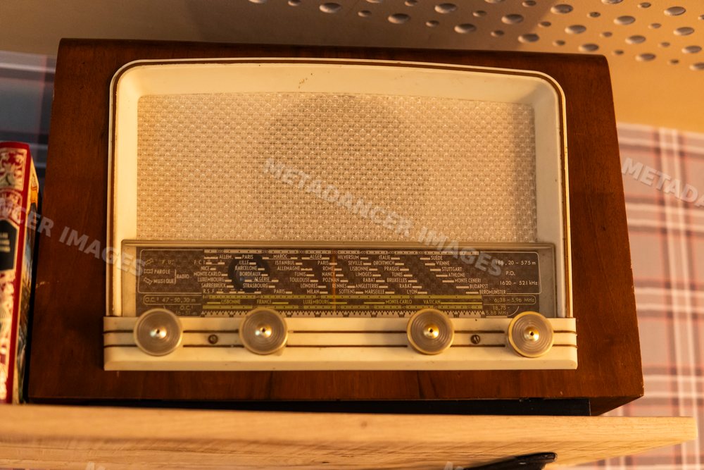 Vintage wooden radio with tuning knobs displayed on a shelf