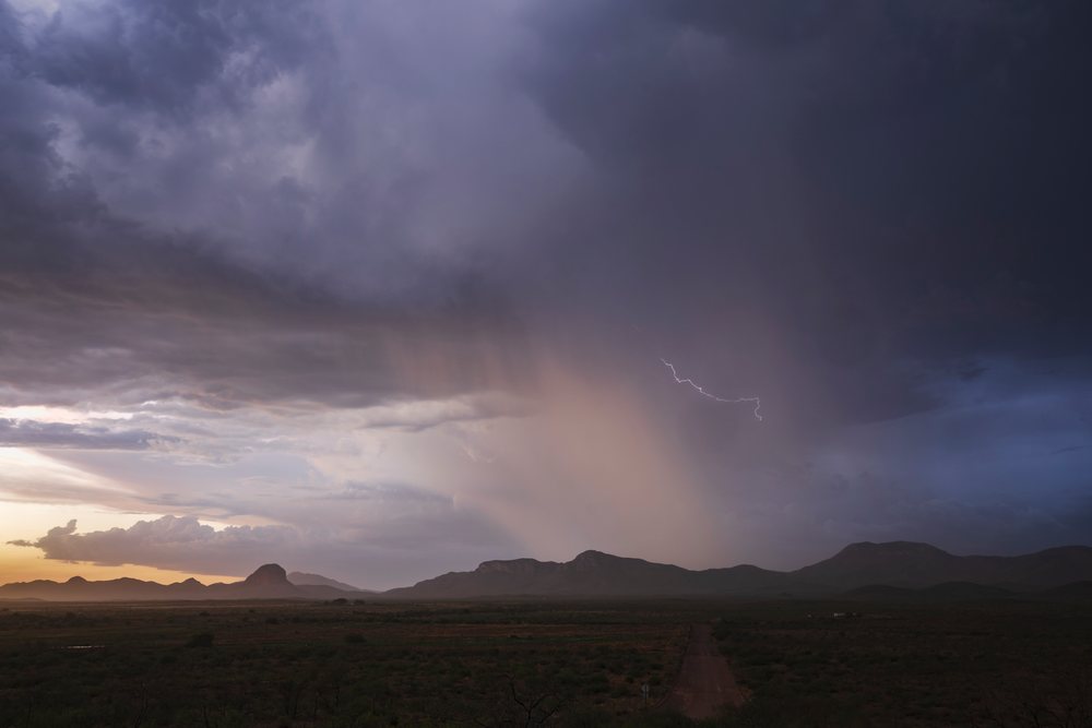 Lightning strikes above the Chiricahua Mountains with a visible rain shaft at Sunset, Storm Chasing, Weather, Environmental Issues, Douglas, Arizona, USA.