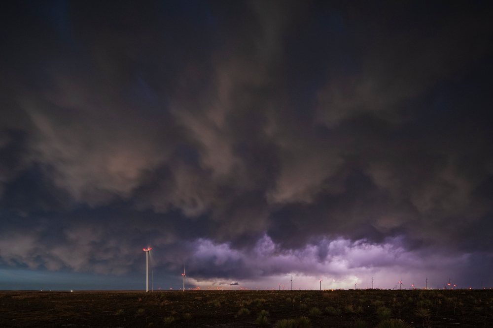 Lightning flashes amid a storm receding with dark clouds over wind turbines in the Great Plains, Storm Chasing, Weather, Environment, Guymon, Oklahoma, USA.
