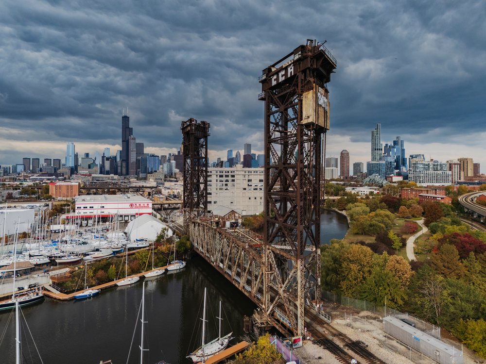 Steel Canal Street Railway Lift Bridge over waterway with Chicago skyline and autumn foliage in an urban park scene, Americana, Historic, Illinois, USA.